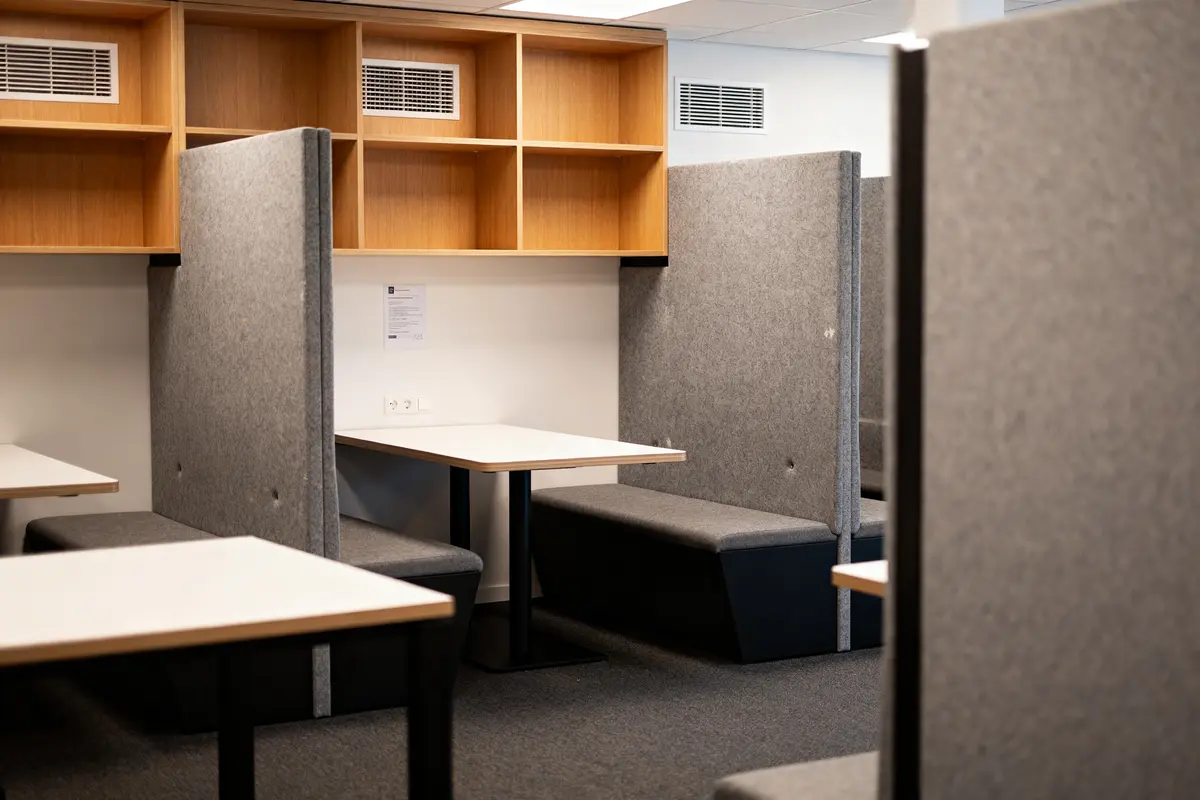 Petite salle de pause avec cabines grises et tables pour entreprise