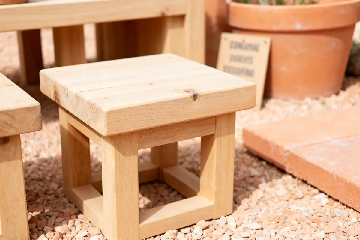 Table d'extérieur en bois dans un salon beige et terracotta sur gravier