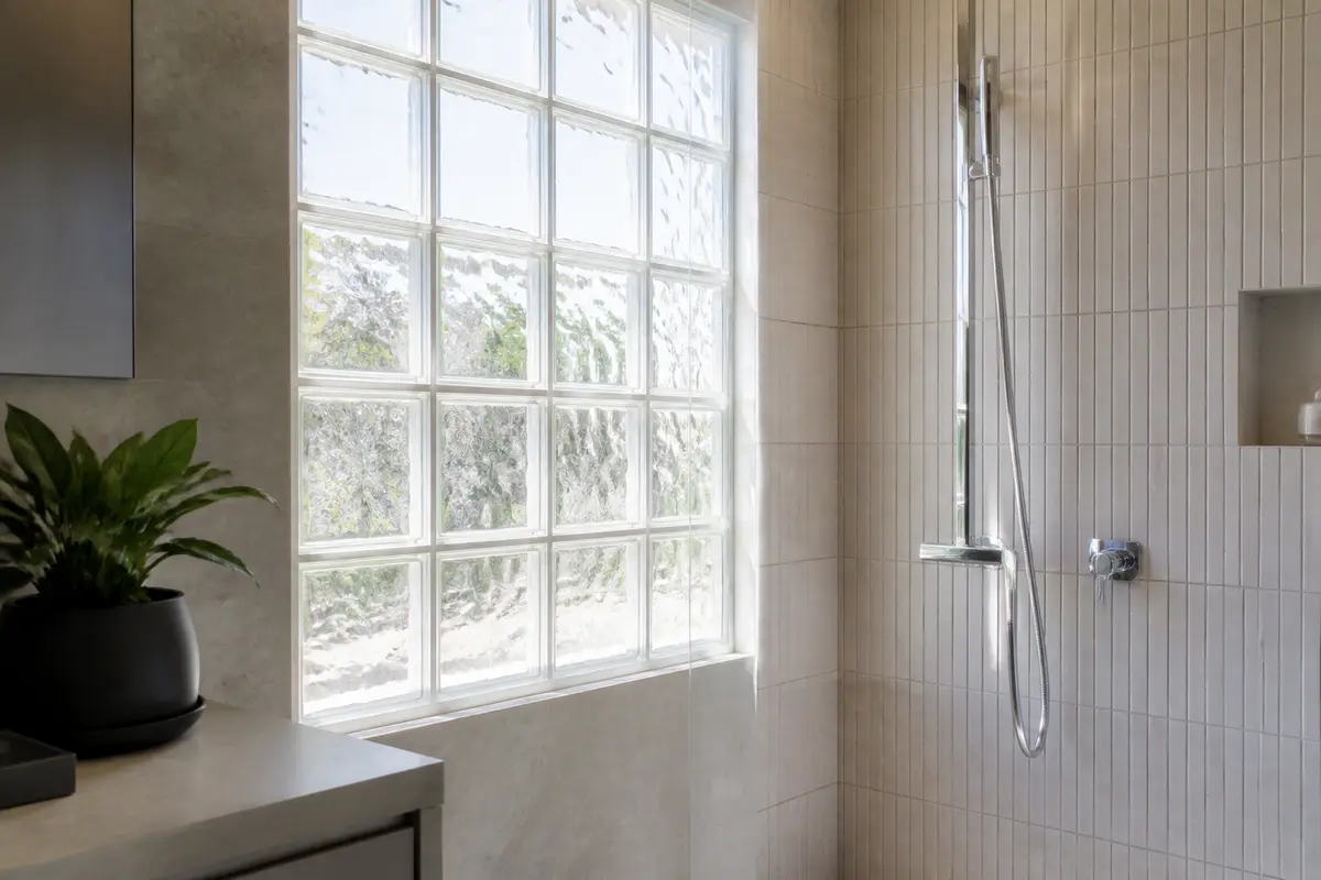 Douche moderne avec carreaux de verre dans une salle de bain minimaliste et lumineuse