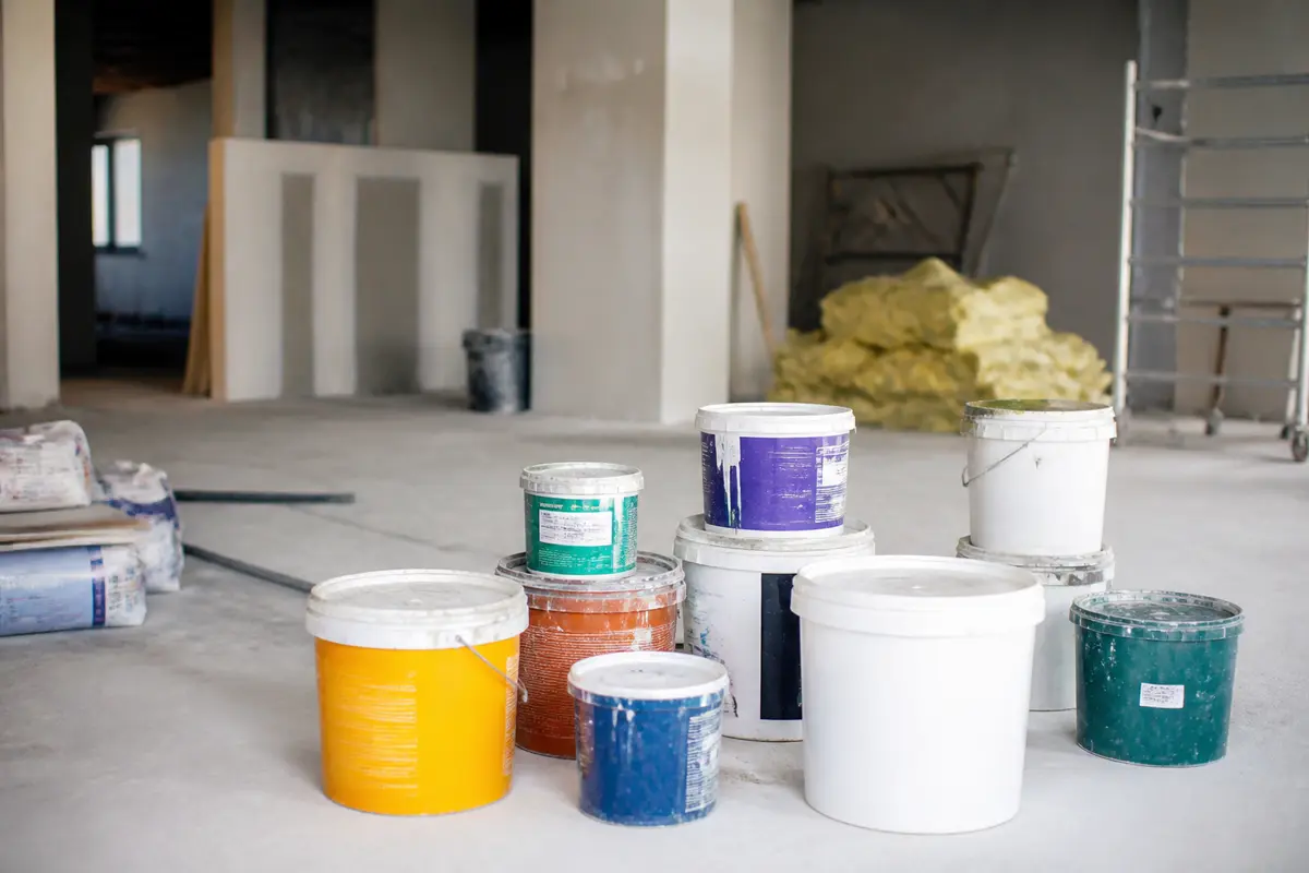 Pots de peintures colorées sur un chantier avec proxichantier.fr couleurs variées sur le sol